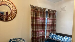 A bedroom with a bed, a mirror, and curtains. - worcester Town home& Gardens (Worcester)