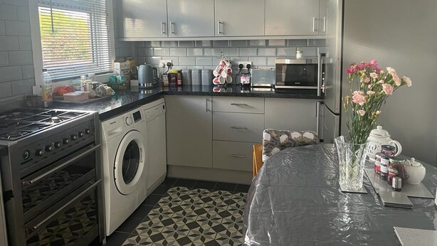 A compact kitchen with a washing machine, microwave, and gas stove. - worcester Town home& Gardens (Worcester)