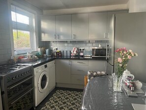 A compact kitchen with a washing machine, microwave, and gas stove.