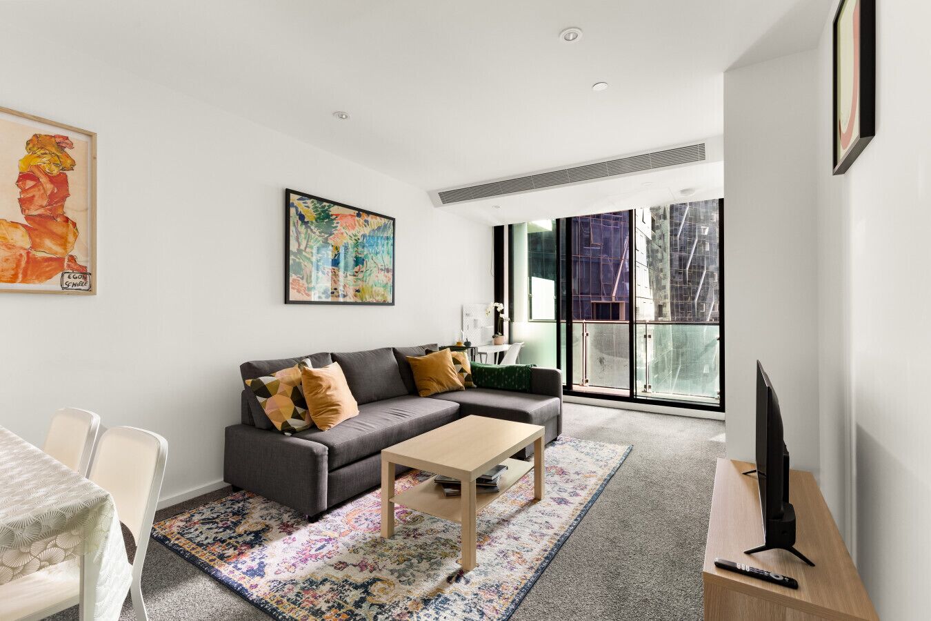 A modern living room with a sofa, coffee table, and a TV on a stand.