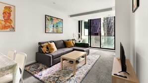A modern living room with a sofa, coffee table, and a TV on a stand.