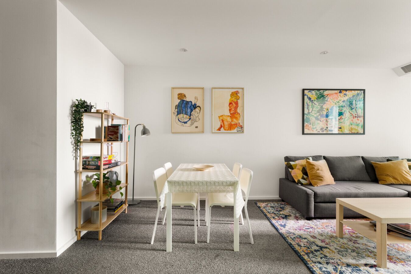 Ein Wohnzimmer mit Esstisch, Sofa und Kunstwerken an den Wänden.