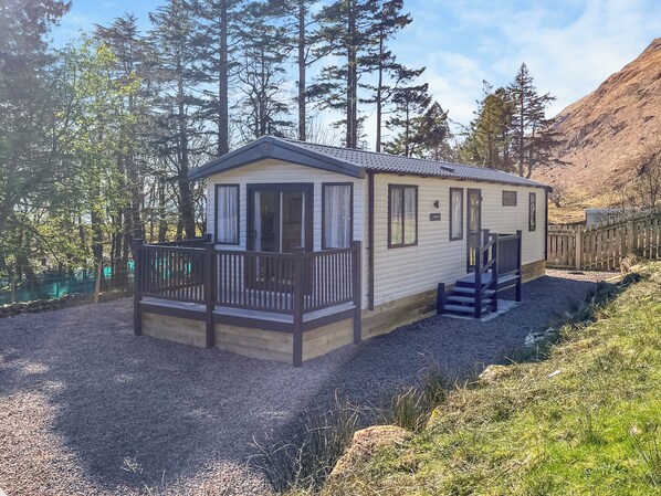 Ein Bungalow mit Balkon, einer kleinen Veranda und einer Treppe zu einer Terrasse.