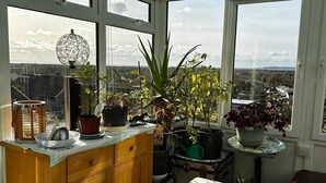 Un invernadero con un aparador de madera, un banco blanco y diversas plantas en macetas.