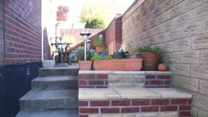 Una escalera de ladrillo que conduce a una pequeña zona de estar al aire libre con una mesa y sillas.