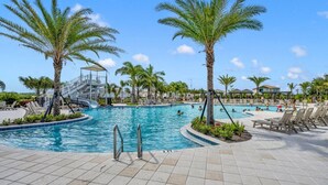 A pool area with palm trees, lounge chairs, and a water slide.