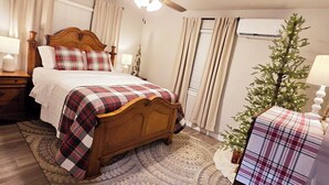 Une chambre avec un lit en bois, un ventilateur de plafond, un sapin de Noël et un tapis à motifs.
