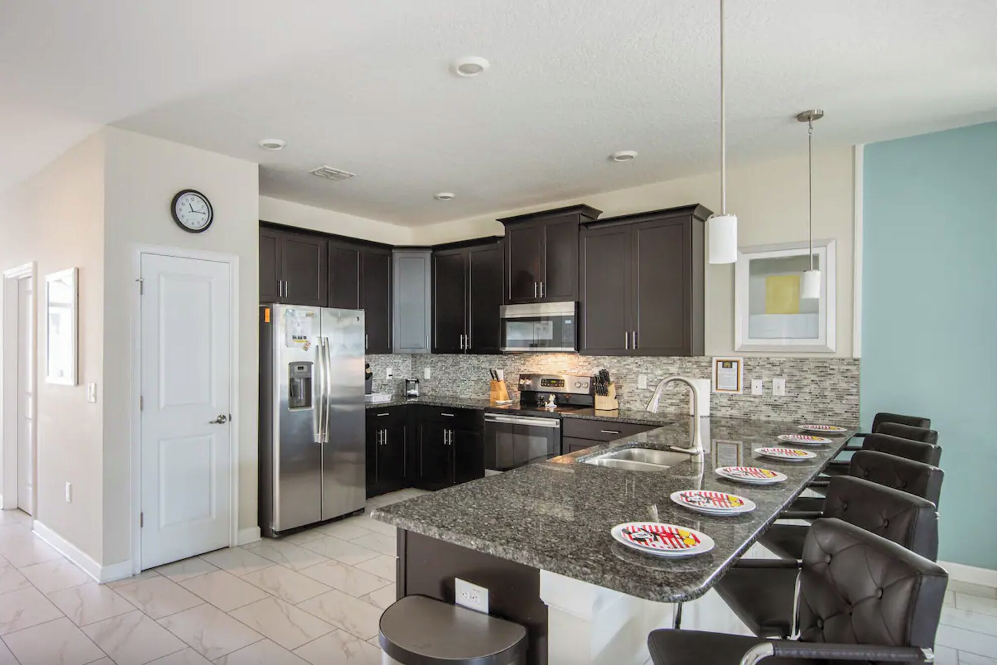 A modern kitchen with dark cabinets, stainless steel appliances, a granite countertop, and a breakfast bar with seating.