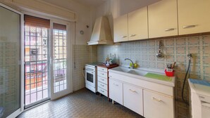 Eine kleine Küche mit Einbauofen, Spüle und Fenster mit Blick auf den Balkon.