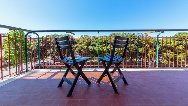 Ein Balkon mit zwei Stühlen und einem roten Metallzaun.