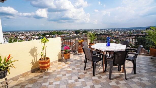 A terrace with a table and chairs, potted plants, and a view of a cityscape. - Casa Colonial San Antonio, ideal for family and friends (Private parking)  (Cali)