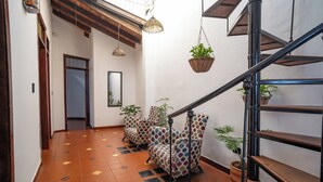 A staircase with a wooden handrail and a metal banister, leading to a landing area with patterned chairs and hanging plants. - Casa Colonial San Antonio, ideal for family and friends (Private parking)  (Cali)