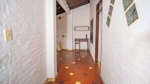 A narrow hallway with white textured walls, a tiled floor with geometric patterns, and a wooden ceiling beam. - Casa Colonial San Antonio, ideal for family and friends (Private parking)  (Cali)