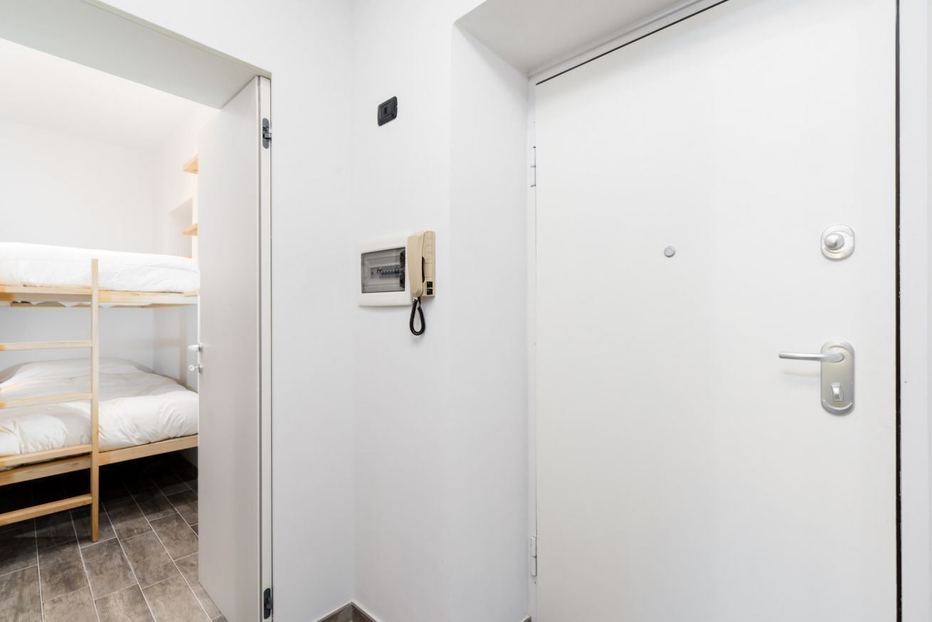 A room with a bunk bed, a door with a lock, and a small window with a phone.