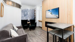 A modern living room with a sofa, two armchairs, a TV, and a wooden accent wall.