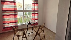 Ein Zimmer mit Balkon, einem Tisch, zwei Stühlen und einer Pendelleuchte.