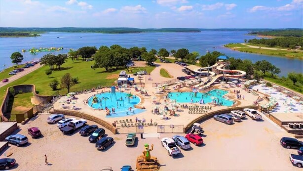 A resort with multiple swimming pools, a water park, and a parking area with cars. - Large porch offers beautiful views of the lake. Enjoy unique interior design! (Mannford)