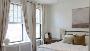 A bedroom with a bed, a bedside table, a lamp, and a window with curtains. - Close to Wellspan, York College, Appell! Washer/dryer in unit. (York)