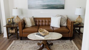 A living room with a brown leather sofa, a round coffee table, and two lamps on side tables. - Close to Wellspan, York College, Appell! Washer/dryer in unit. (York)