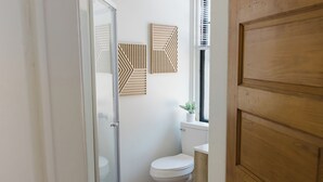 A bathroom with a white toilet, wooden cabinet, and two geometric wall art pieces. - Close to Wellspan, York College, Appell! Washer/dryer in unit. (York)