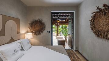 Una moderna camera d'albergo con un letto grande, un ventilatore a soffitto e vista sul giardino esterno.