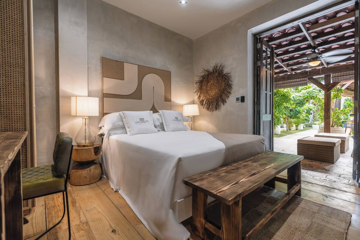 A bedroom with a bed, bedside tables, a chair, and a wooden bench.