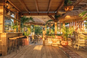 A wooden deck with bar stools, wicker chairs, and potted plants. - Hotel Casa Don Luis Cap Cana by Faranda Boutique (Punta Cana)