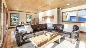 A spacious living room with a large leather sofa, wooden coffee table, and large windows offering natural light. - Tranquil cabin on Warm River, Ashton
Boat ramp access-fly fishing haven.  (Ashton)