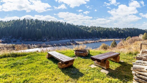 A picnic area with two wooden benches, a fire pit, and a stack of logs. - Tranquil cabin on Warm River, Ashton
Boat ramp access-fly fishing haven.  (Ashton)