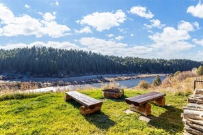 A picnic area with two wooden benches, a fire pit, and a stack of logs. - Tranquil cabin on Warm River, Ashton
Boat ramp access-fly fishing haven.  (Ashton)