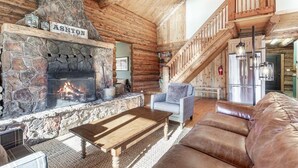 A log cabin interior with a stone fireplace, a wooden staircase, and a leather sofa. - Tranquil cabin on Warm River, Ashton
Boat ramp access-fly fishing haven.  (Ashton)