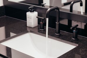 Ein modernes Badezimmer mit schwarzem Waschtisch, einer weißen Spüle und einem schwarzen Wasserhahn.