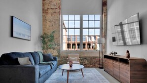 A modern living room with a grey sofa, a round coffee table, and a wooden cabinet. - Spacious Sanctuary | Near DT Action (Greenville)