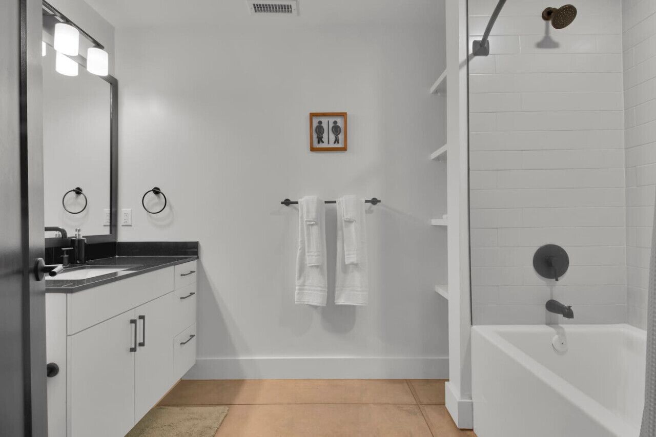 Uma casa de banho moderna com lavatório, espelho, porta-toalhas e chuveiro.