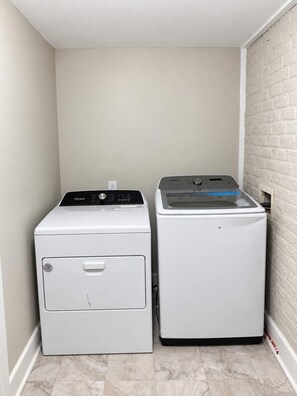 A laundry room with two front-loading washing machines and a dryer.