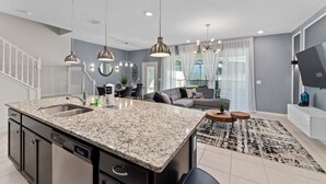 Eine moderne Küche mit Granit Arbeitsplatten, Edelstahlgeräten und Pendelleuchten.