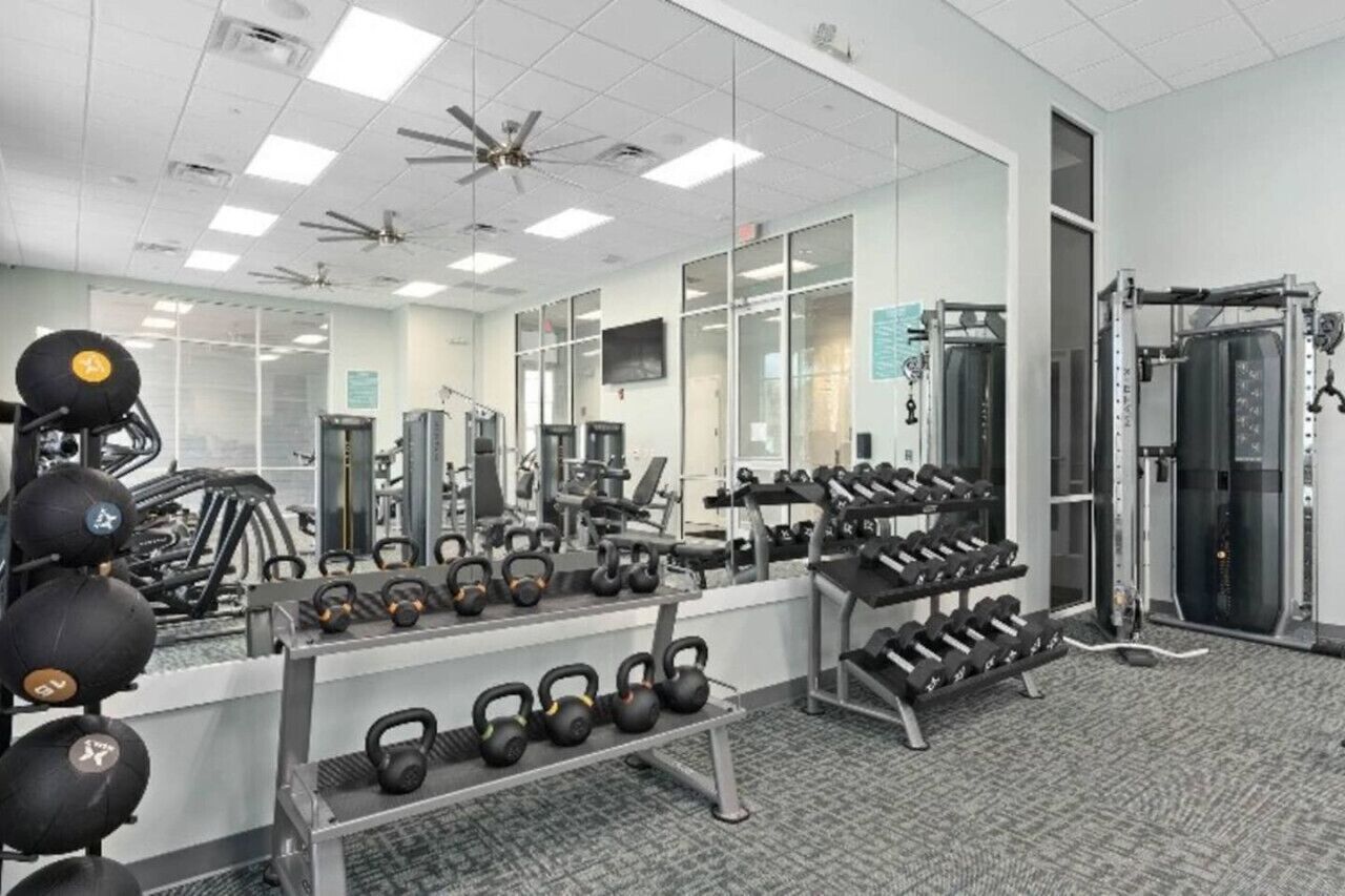 A gym with various exercise equipment, including kettlebells, dumbbells, and weight machines.