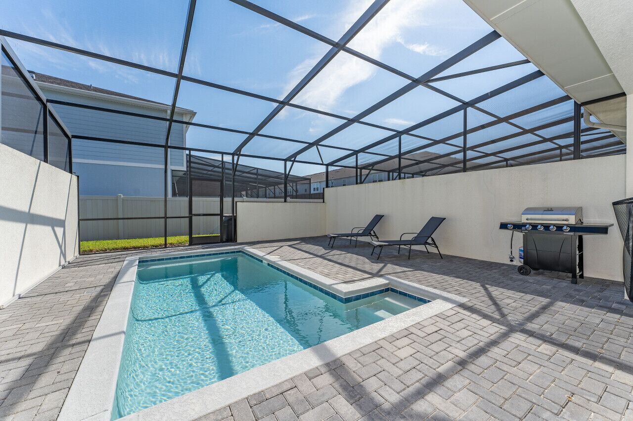 Une piscine extérieure couverte, dotée de chaises longues et d’un barbecue.