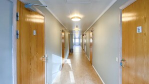 A hotel hallway with wooden doors, a light fixture, and a carpeted floor.