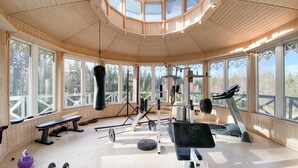 A gym with various exercise equipment, large windows, and a wooden interior.