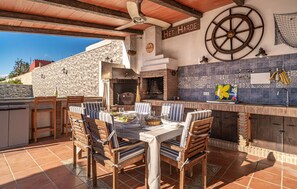 An outdoor dining area with a stone wall, a wooden table, and chairs. - 5 bedroom gorgeous home in Los Barrios (Los Barrios)