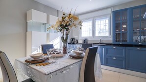 A modern kitchen with blue cabinets, a dining table set for four, and a vase of flowers on the table.