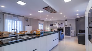 A modern kitchen with a central island, white cabinetry, and a dining area with chairs.