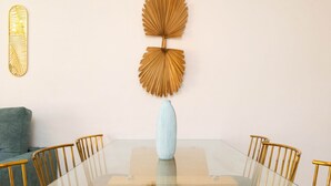 A dining area with a glass table, gold chairs, a light blue vase, and two wall decorations. - Marbella Coastal Comfort (Marbella)