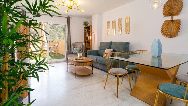 A modern living room with a glass dining table, green sofa, and a large plant. - Marbella Coastal Comfort (Marbella)