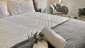 A neatly made bed with a patterned bedspread, a headboard, and a view of greenery outside. - Marbella Coastal Comfort (Marbella)