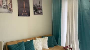 A modern living room with a beige sofa, teal cushions, a white coffee table, and two framed pictures of famous landmarks.
