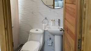 Un baño moderno con inodoro, lavamanos y espejo.