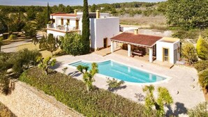 Un alojamiento con piscina, varias edificaciones y abundante vegetación.