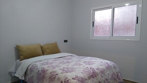 Un dormitorio con una cama, dos almohadas, una ventana y una puerta.